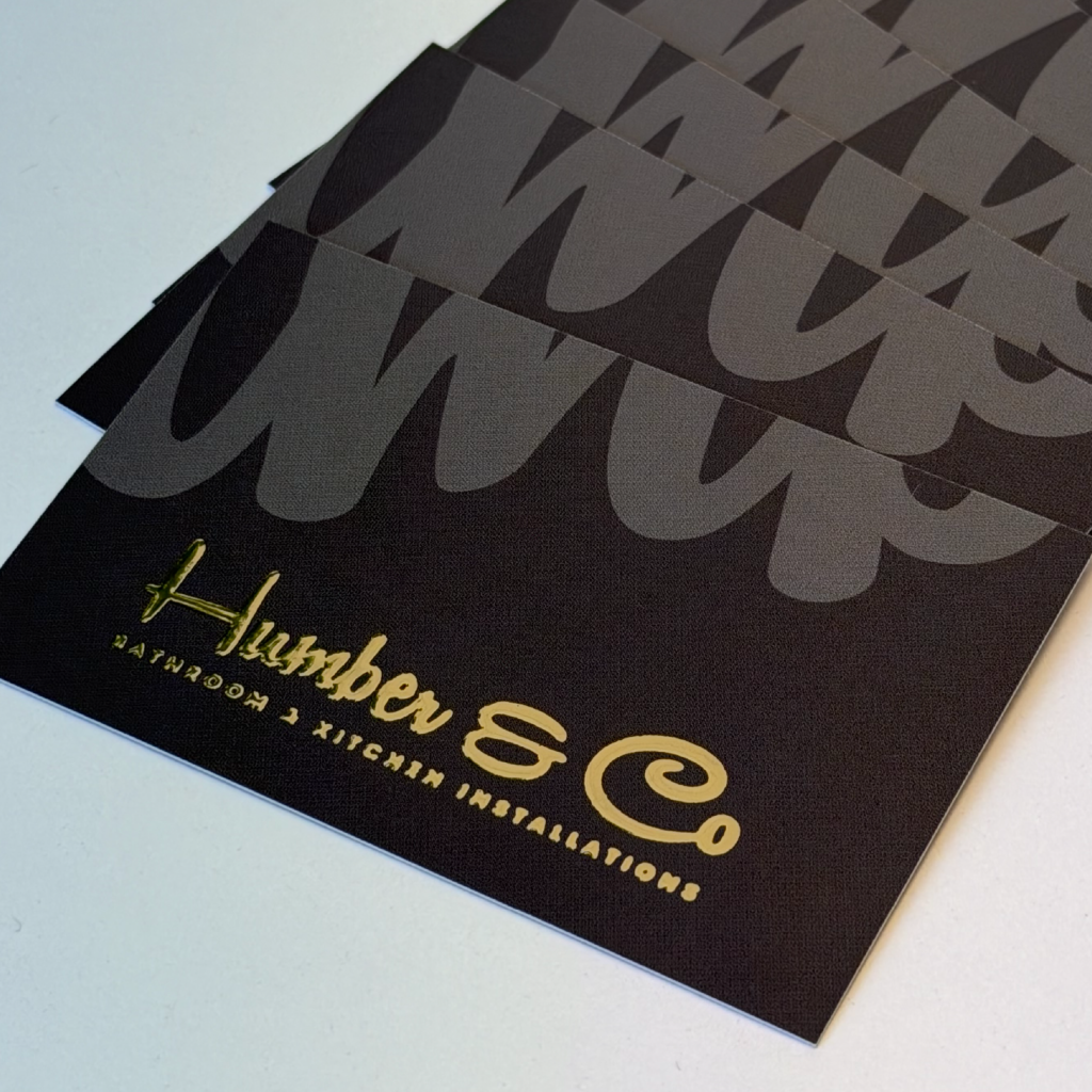 A pile of bespoke black business cards with gold detailing