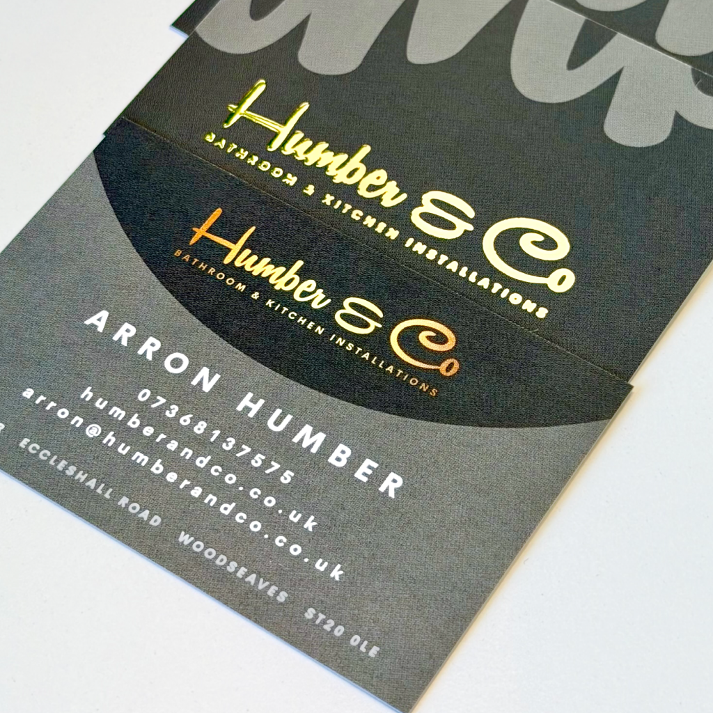 The front and back of a pile of bespoke black business cards with gold detailing