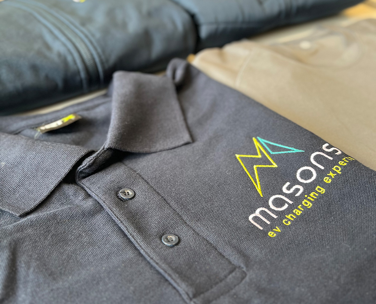 b Embroidered logo design on branded workwear polo shirt for Masons EV Charging Experts